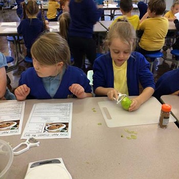 A child pealing an apple with other children reading the recipe